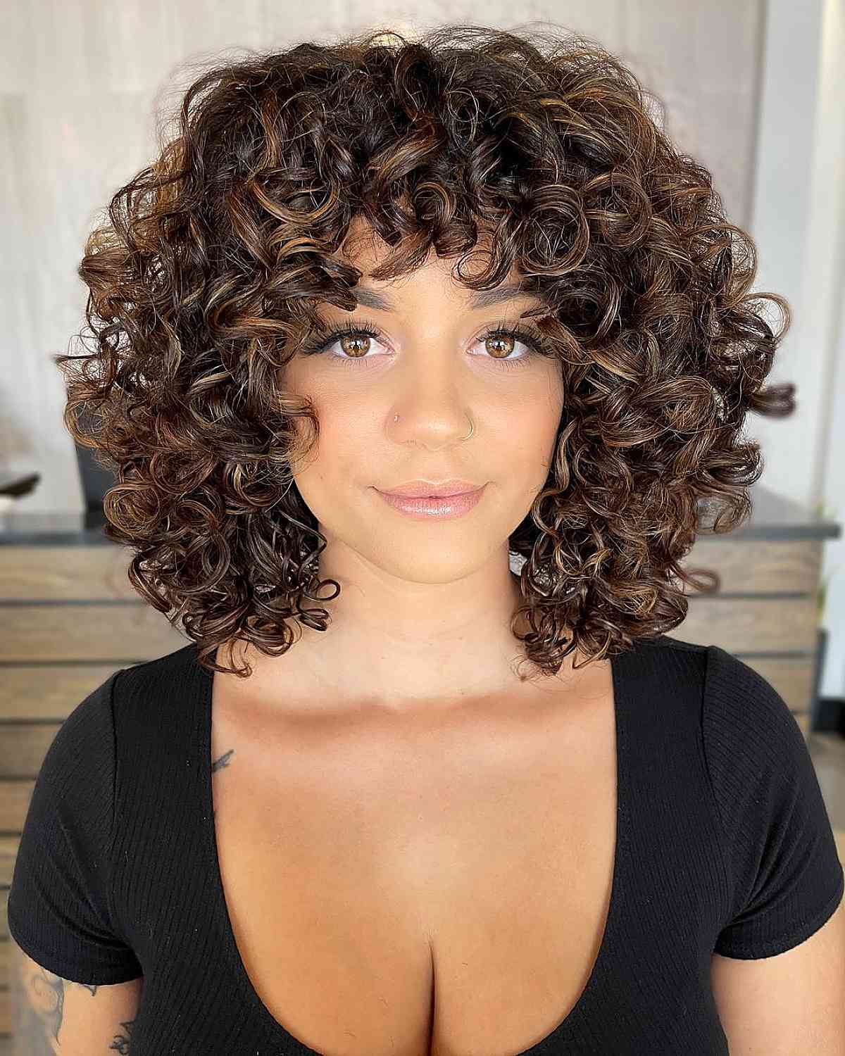 modern short curly hairstyle with brown highlights for natural curls