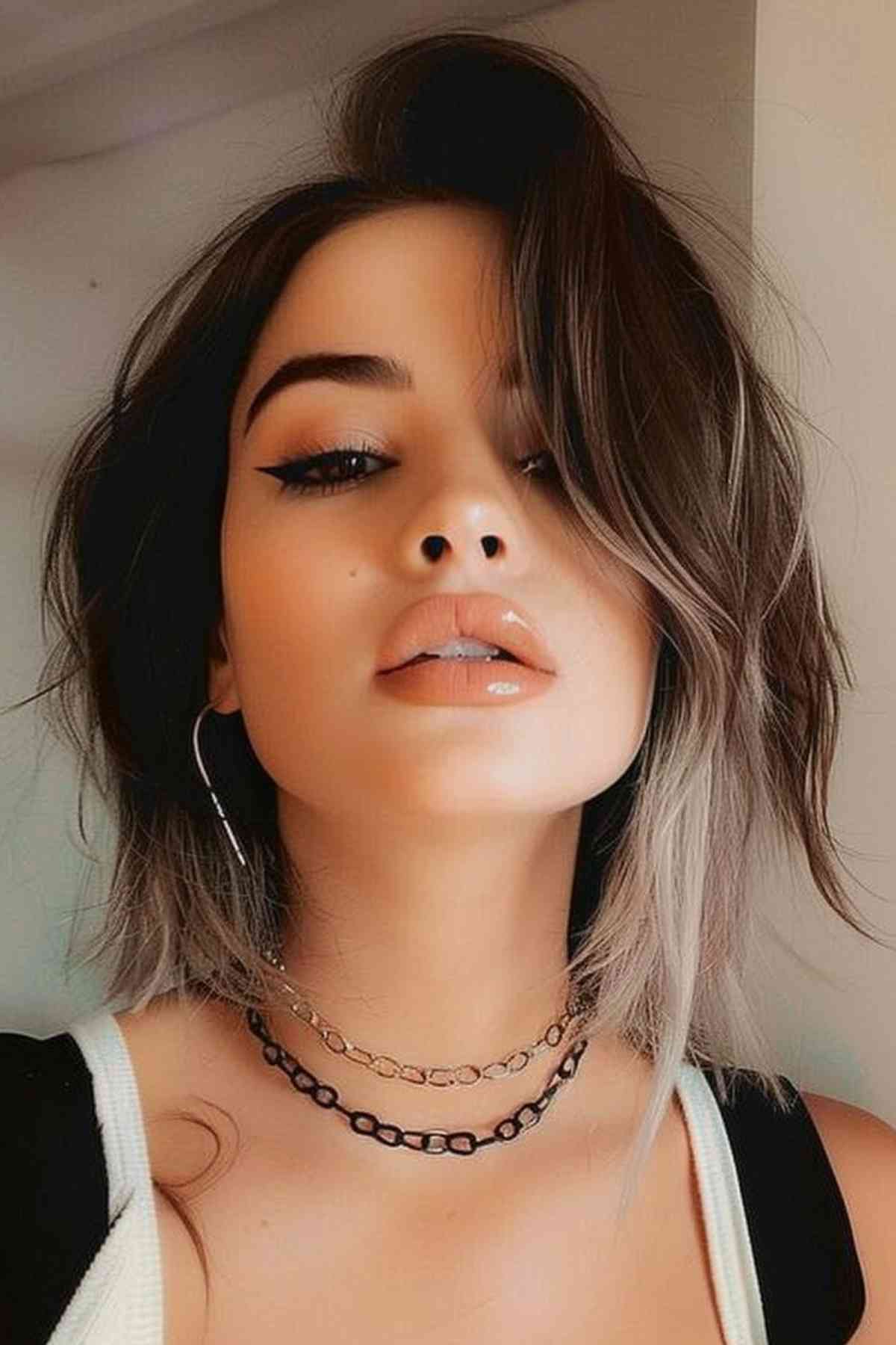Fashionable woman showcasing a neck-length tousled layered haircut with dark roots