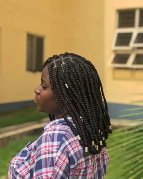 Collarbone length box braids embellished with gold cuffs