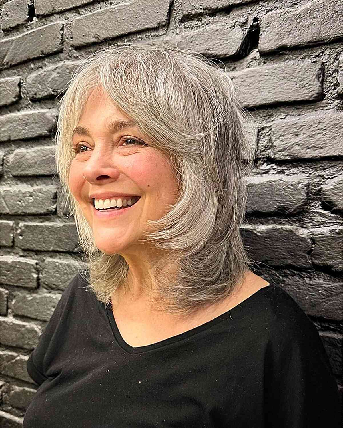 Chic Salt-and-Pepper Shaggy Hairstyle with Curtain Bangs for older women with coarse hair