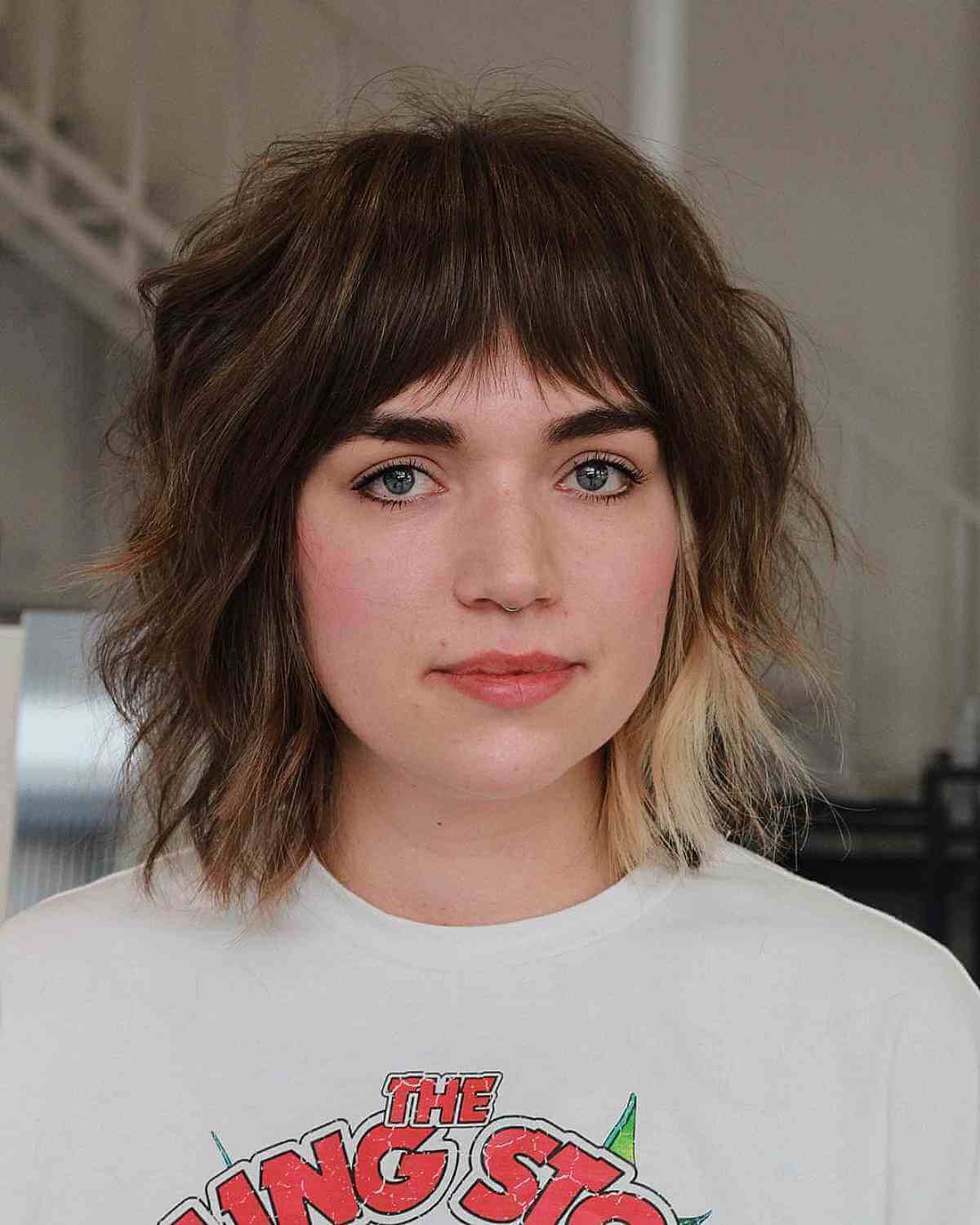 Chic Shaggy Hairstyle with Subtle Blonde Highlights and Bangs