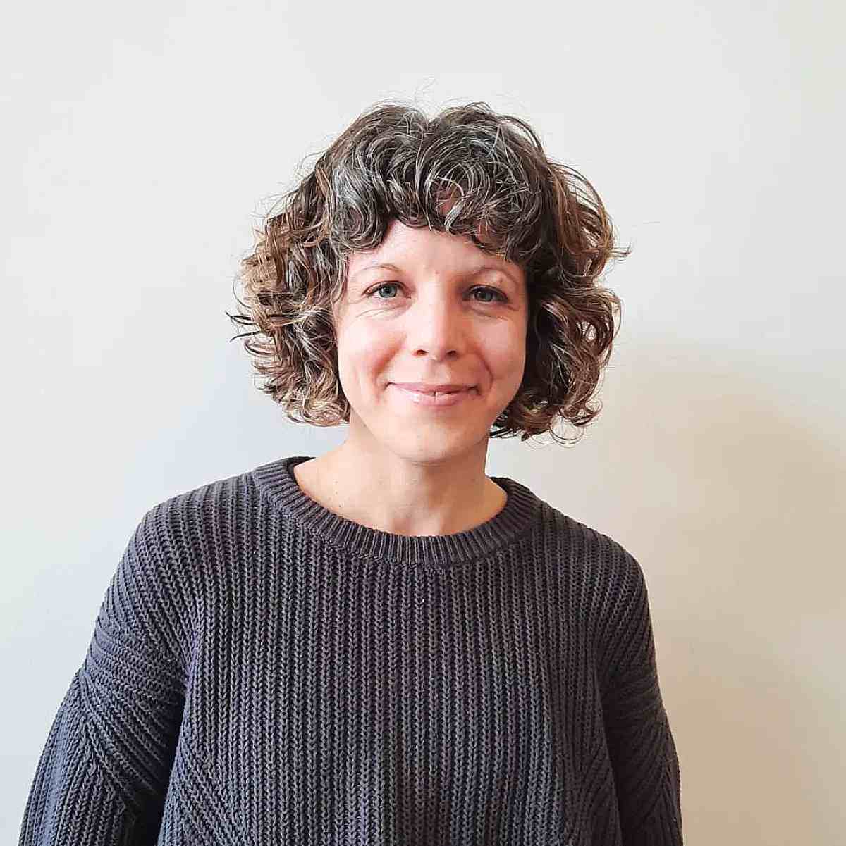 Curly bob hairstyle with compact bangs gender neutral hair