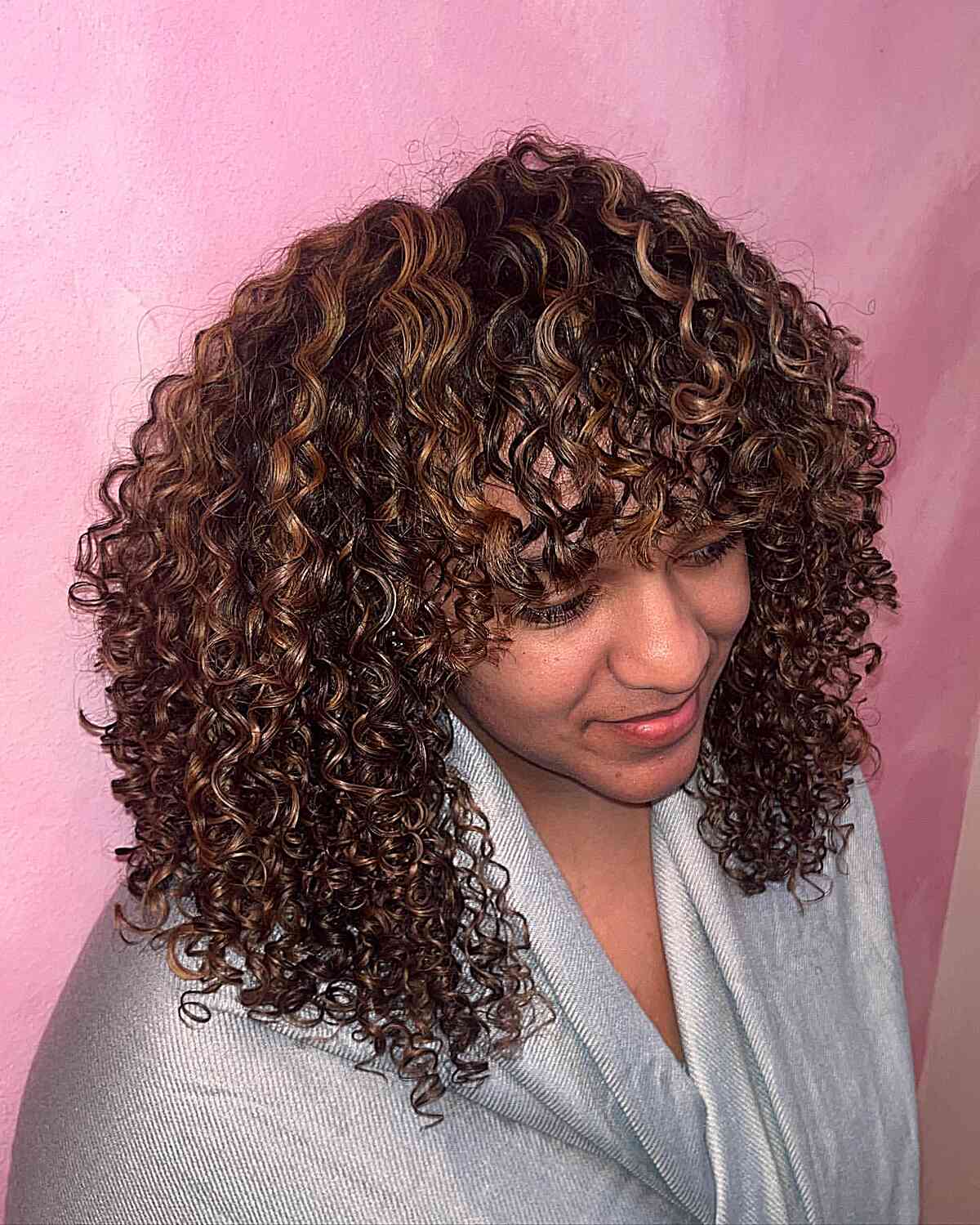 Curly Caramel Hair Highlights for a Medium Layered Haircut with Bangs