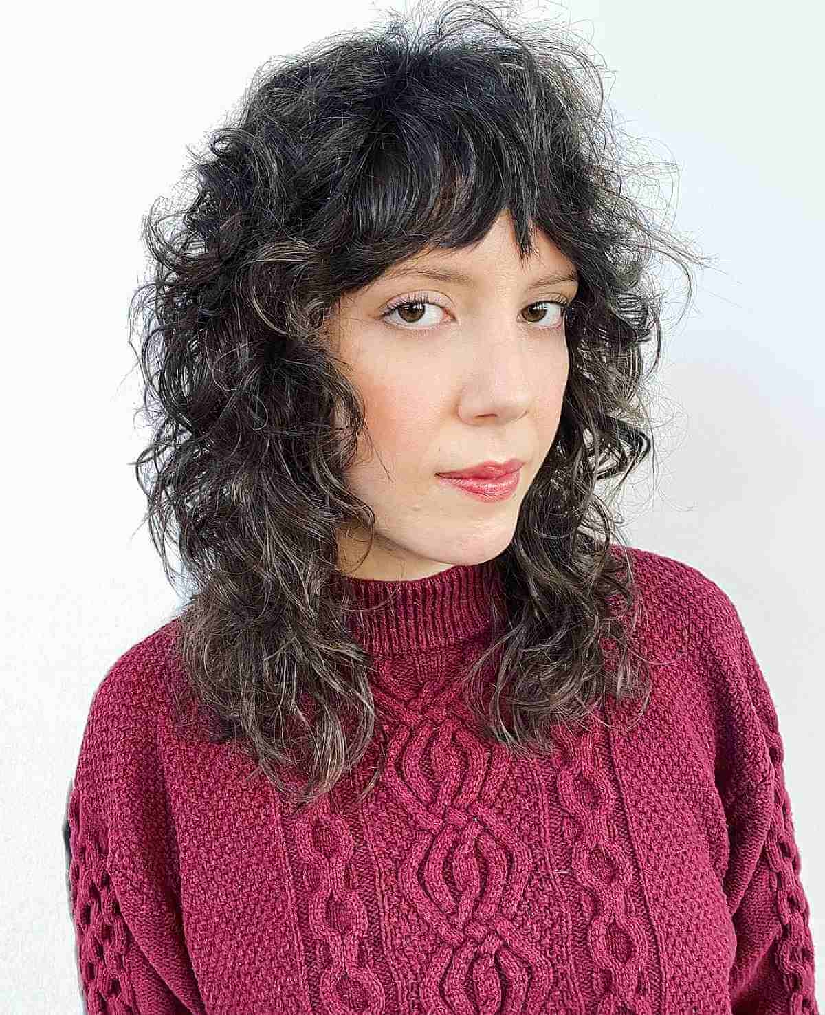 Medium-Length Curly Shag Featuring Razored Layers and Bangs