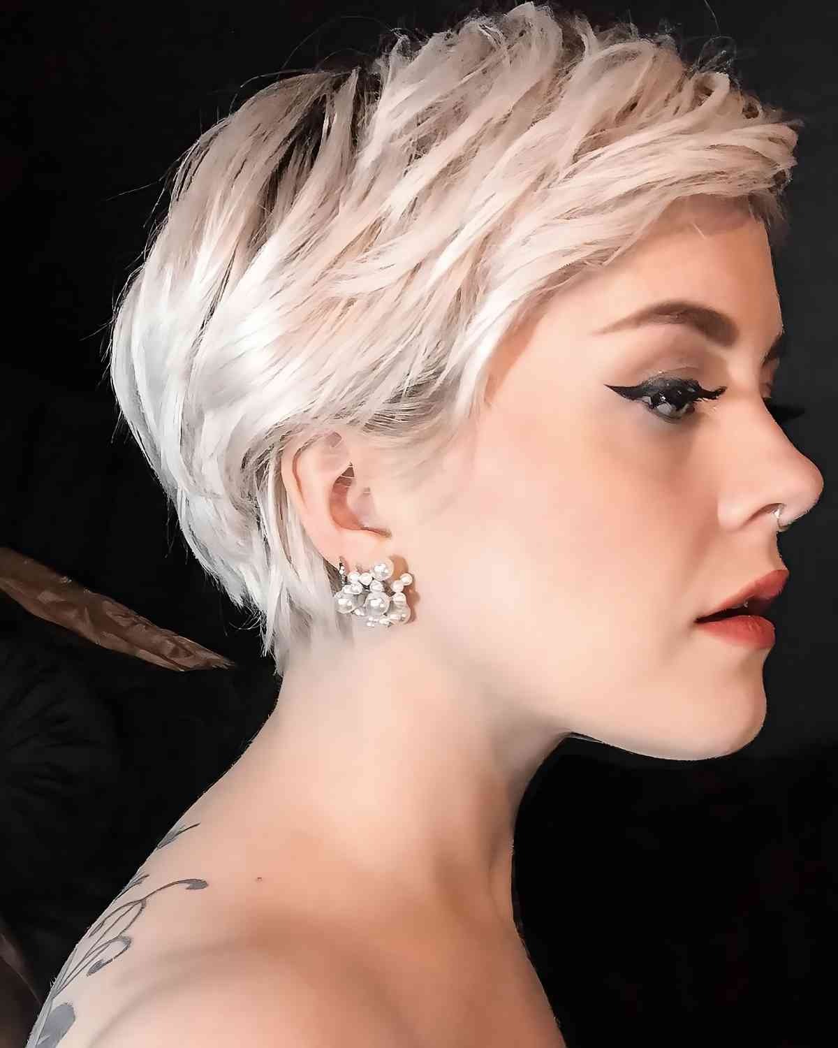 Side view of a platinum blonde pixie haircut featuring textured layers in an inclusive style