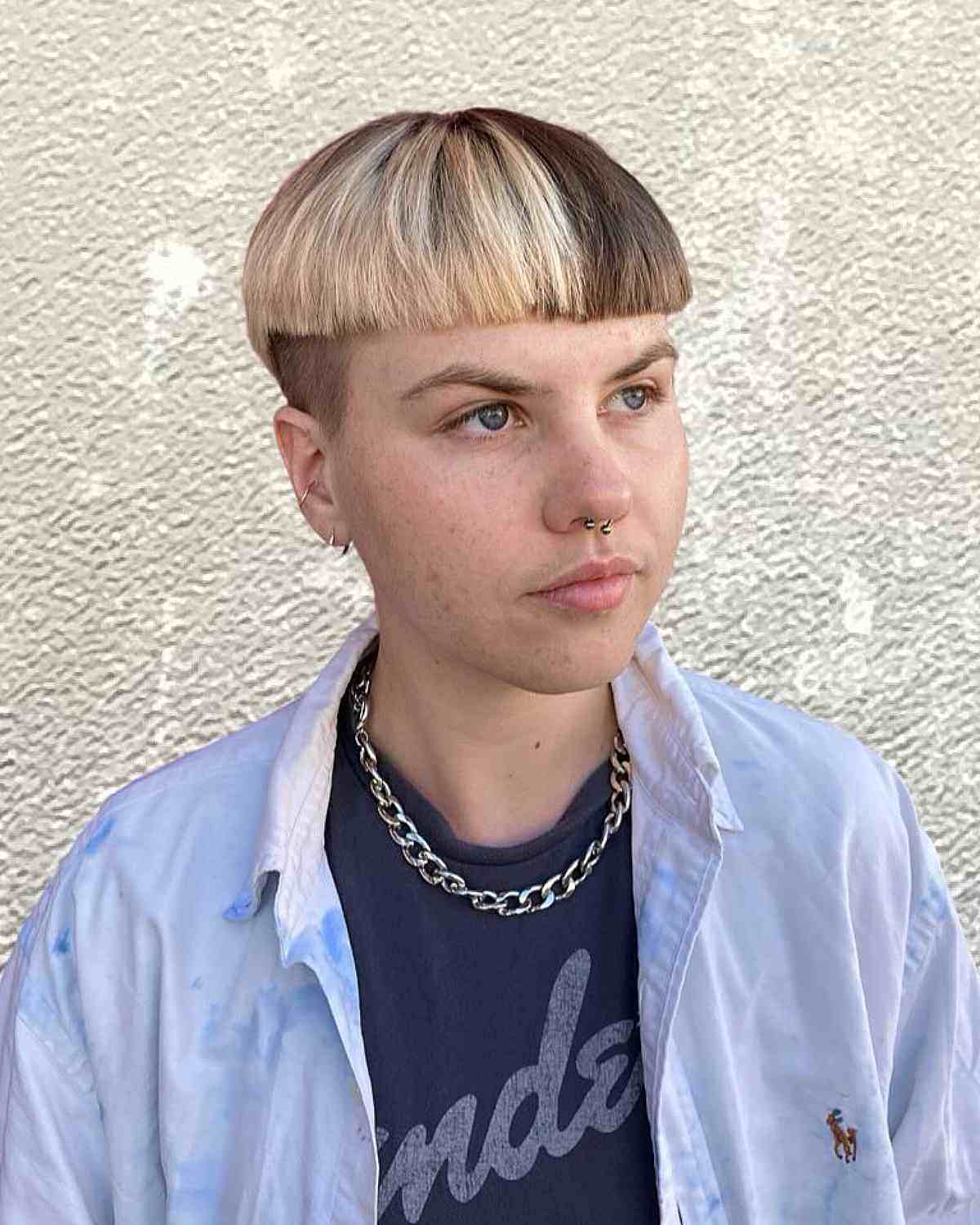 Two-tone bowl cut with platinum blonde and dark brown hair, showcasing a gender neutral undercut