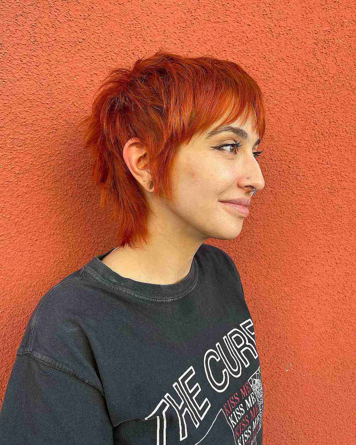 Vibrant red gender neutral shaggy mullet haircut with edgy bangs