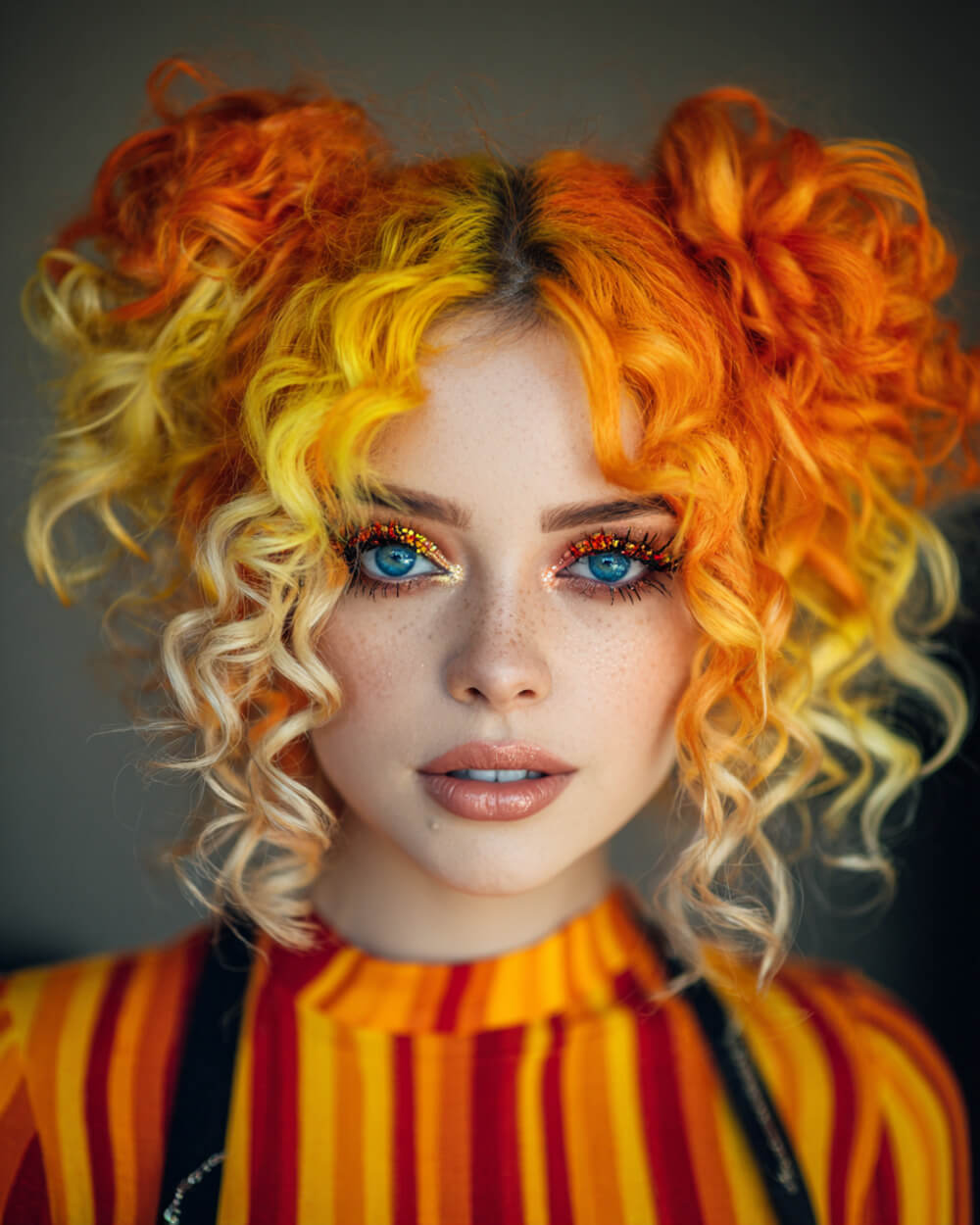 Bright neon orange and yellow curls in space buns, bold Halloween hairstyle