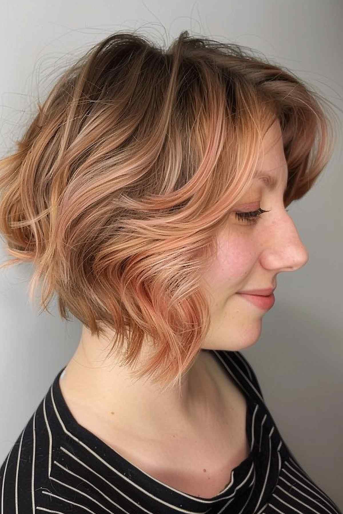 Short, wavy hairstyle with peach blonde highlights adding dimension and a warm, modern appeal, ideal for enhancing facial features and easy maintenance.