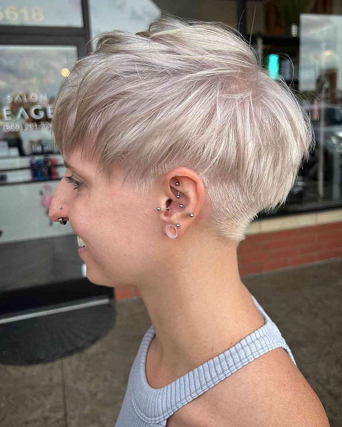 Side view of a woman with a platinum blonde undercut pixie gender neutral haircut