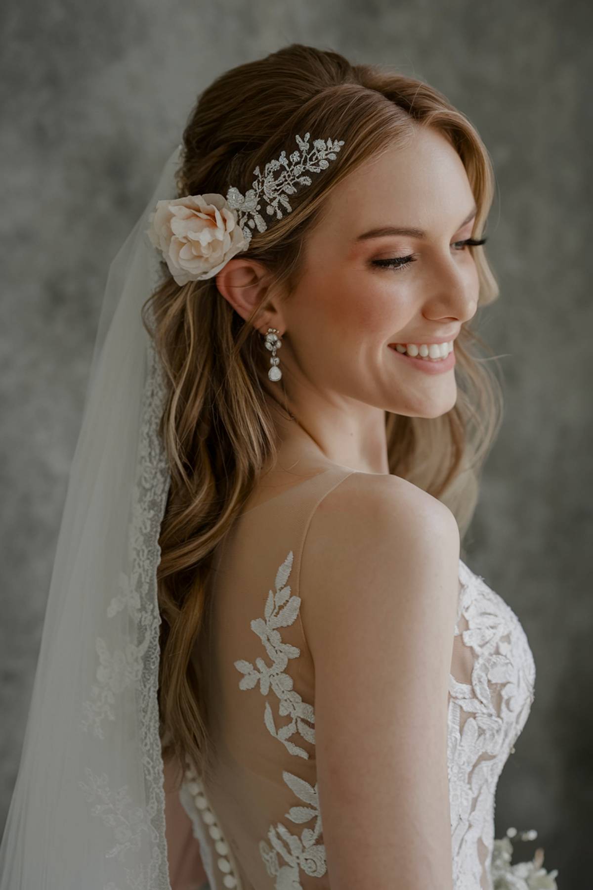 Straight half-up wedding hairstyle with veil and floral accessory