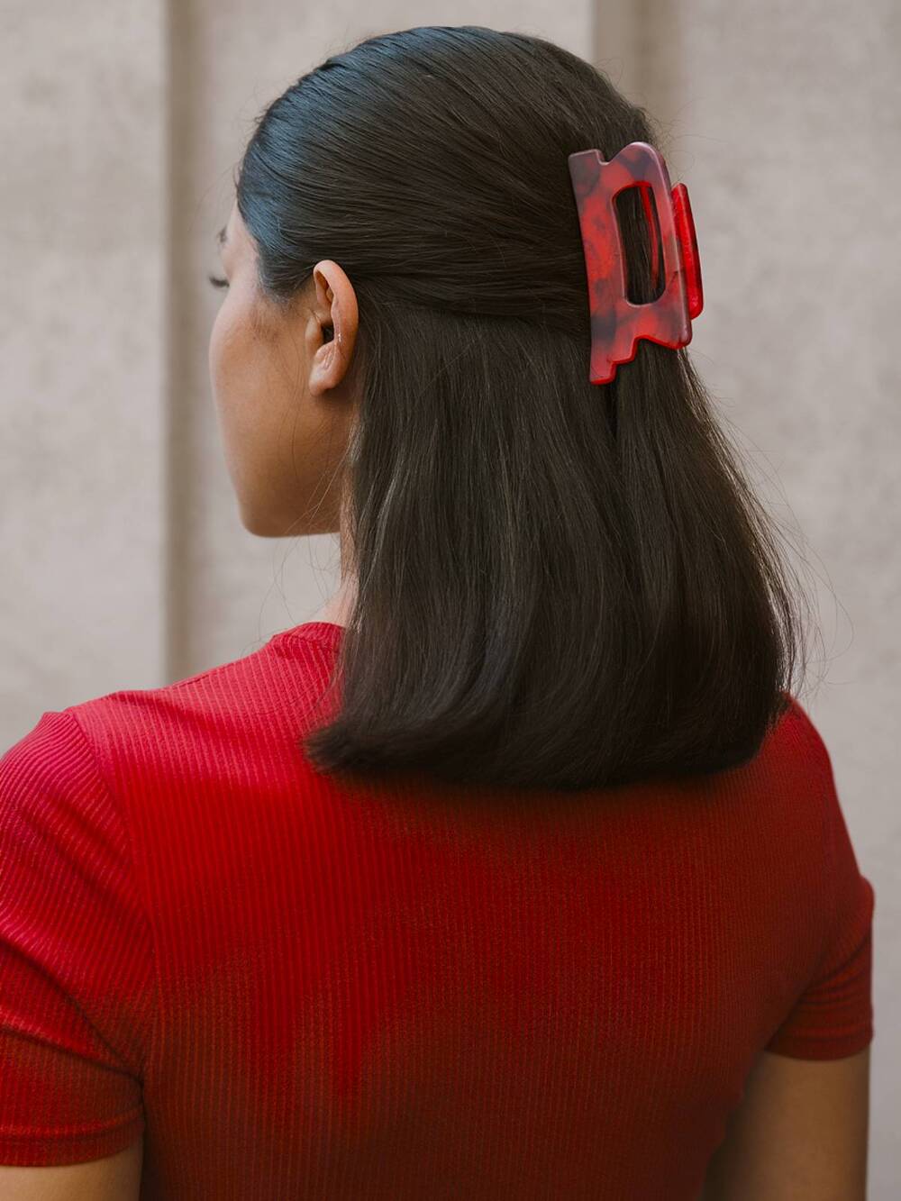 Simple and stylish half-up hairstyle with a bold hair clip on sleek shoulder-length hair