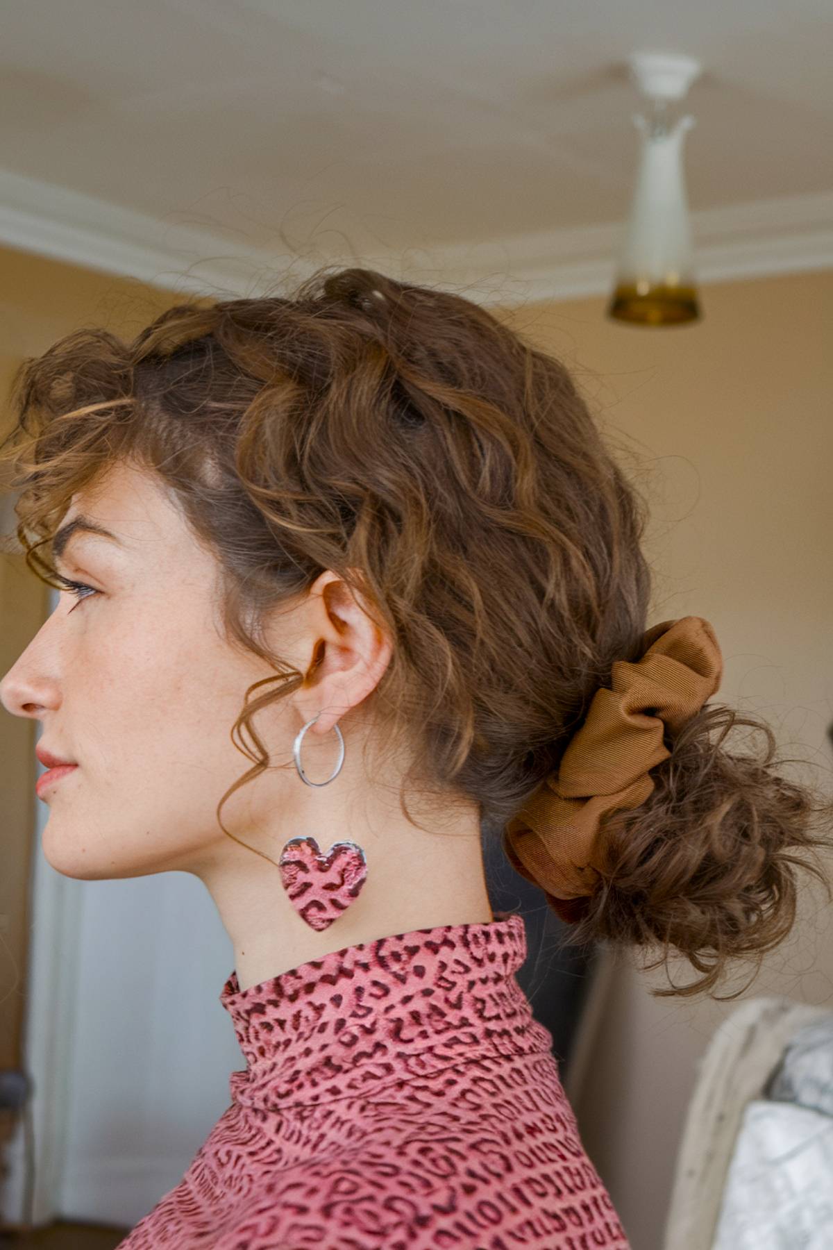 Low curly bun secured with a scrunchie for an easy, casual style