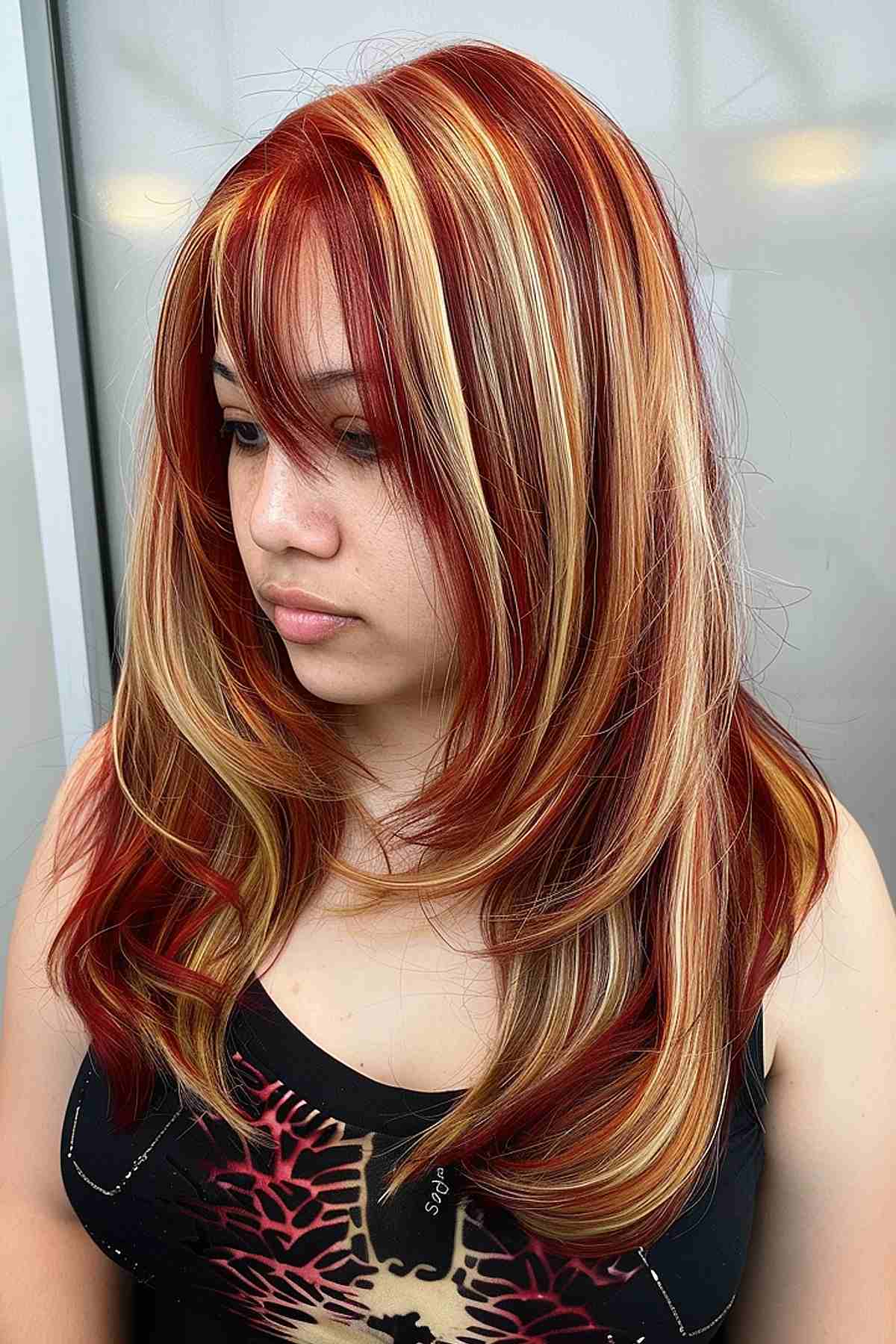 Medium-length red hair with chunky blonde highlights and blunt bangs