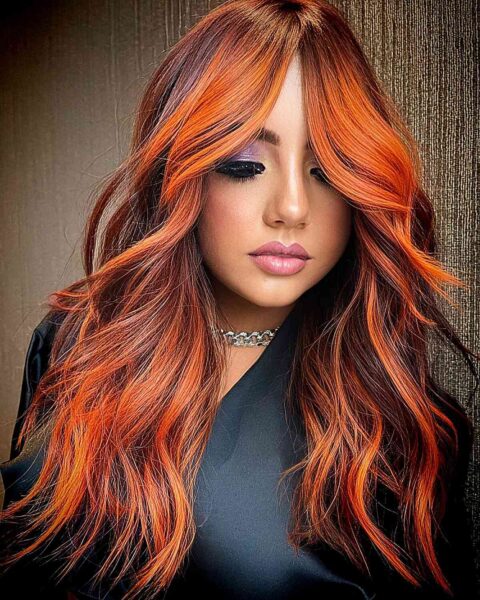 A Reddish Copper Balayage on long hair with long curtain fringe and dark roots