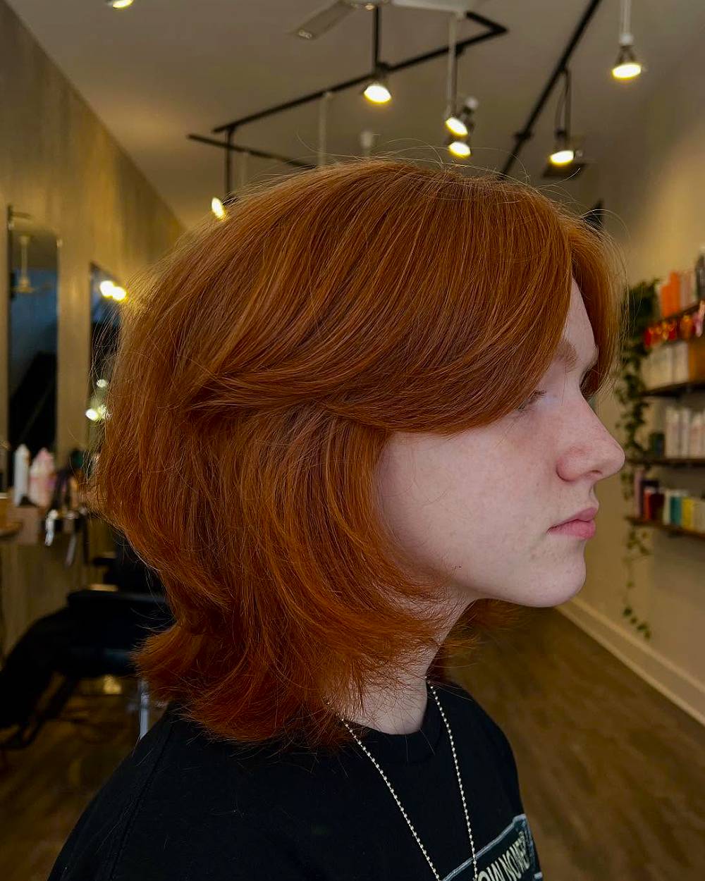 Retro wolf cut with soft layers and curtain bangs on thick, copper-red medium-length hair