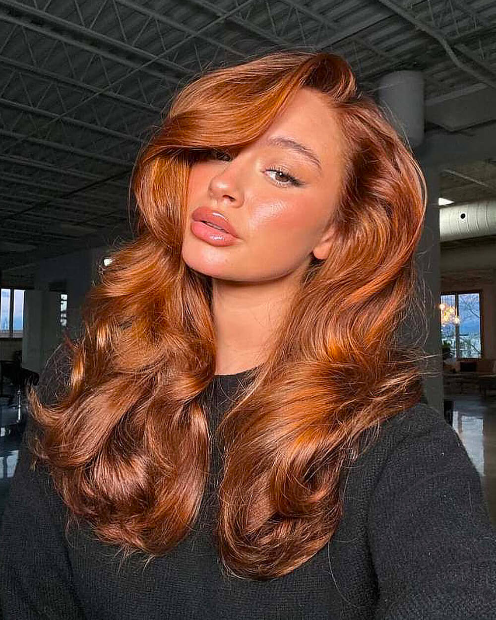 Long copper hair with voluminous waves and rich dimensional gloss styled in a deep side part
