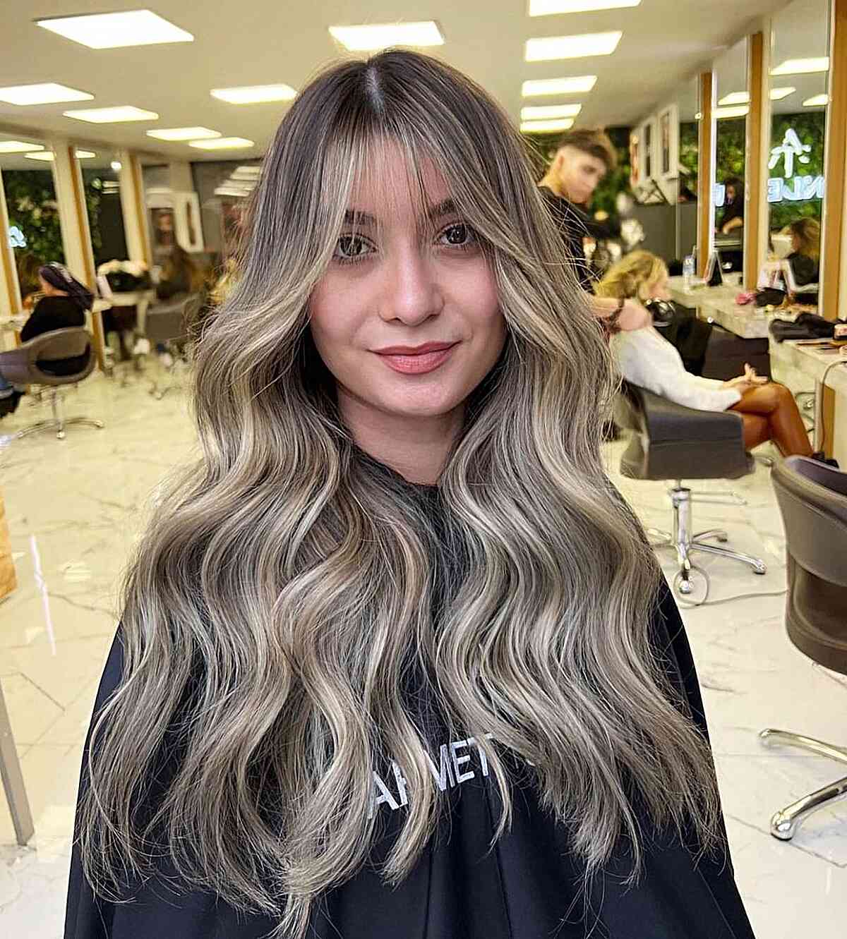 Dark-Rooted Sandy Blonde Balayage Highlights and Wispy Bangs for Lengthy Locks