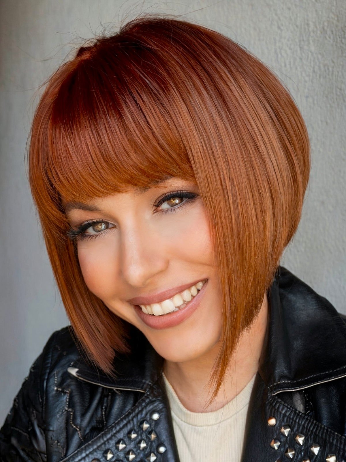 Bold inverted bob with sharp angles and blunt fringe in copper color