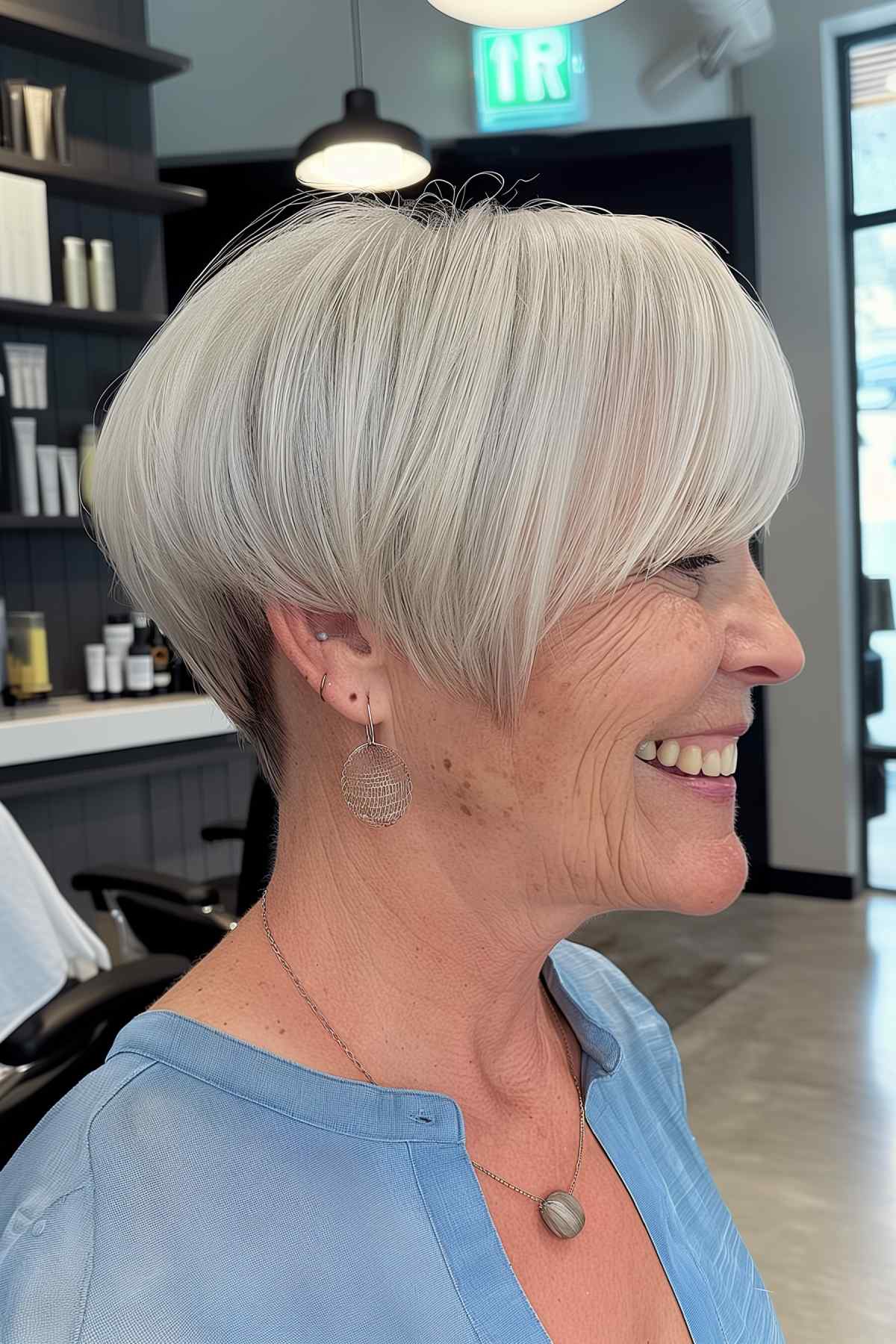 A woman with a bob hairstyle featuring an undercut and shiny silver blonde hair color.