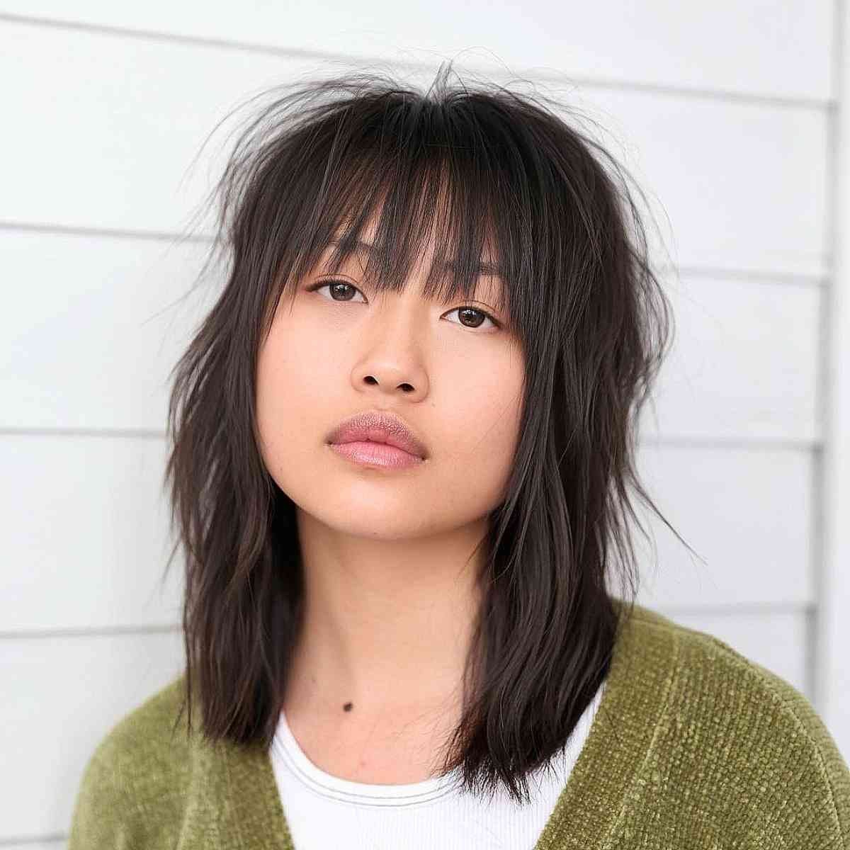 Shaggy shoulder-length haircut with gender neutral wispy bangs