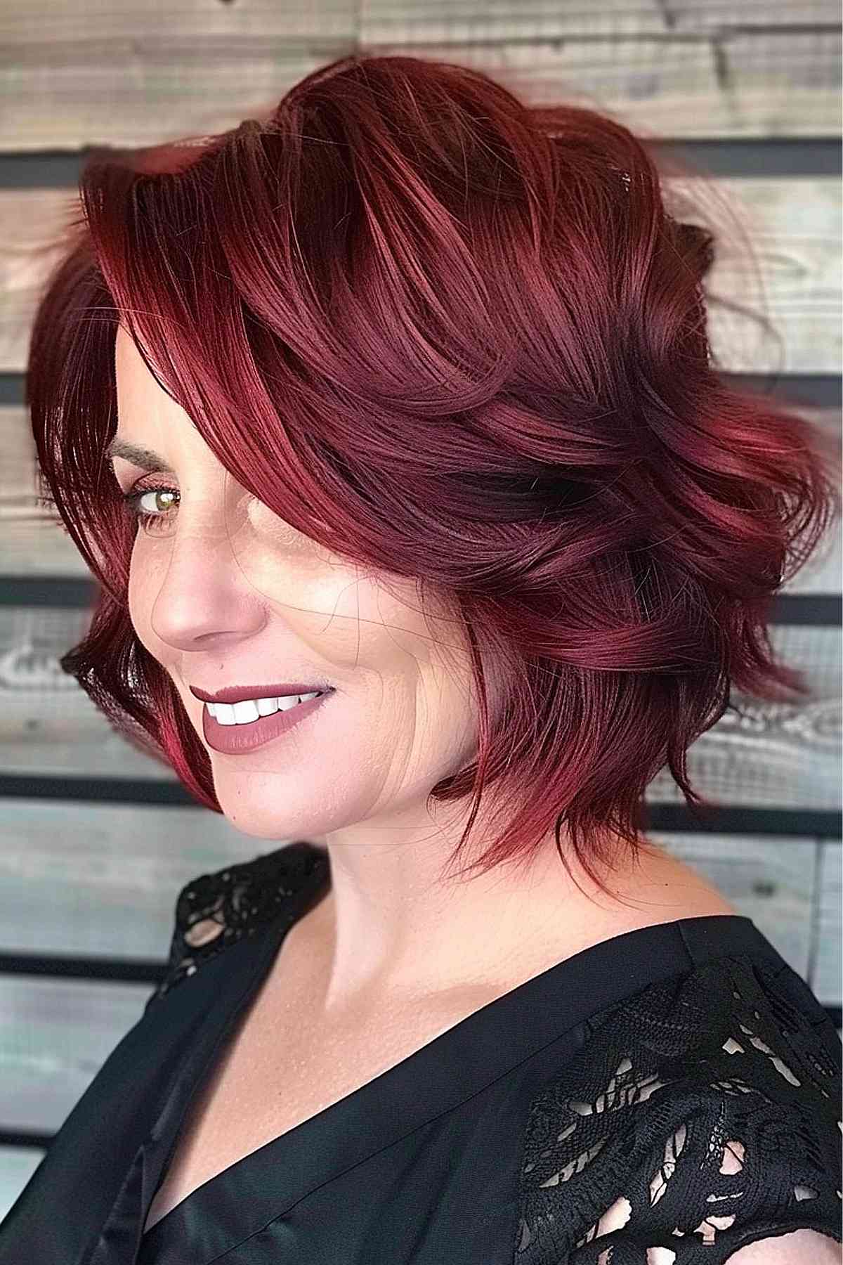 Short feathered cherry red hairstyle, adding volume to fine hair.
