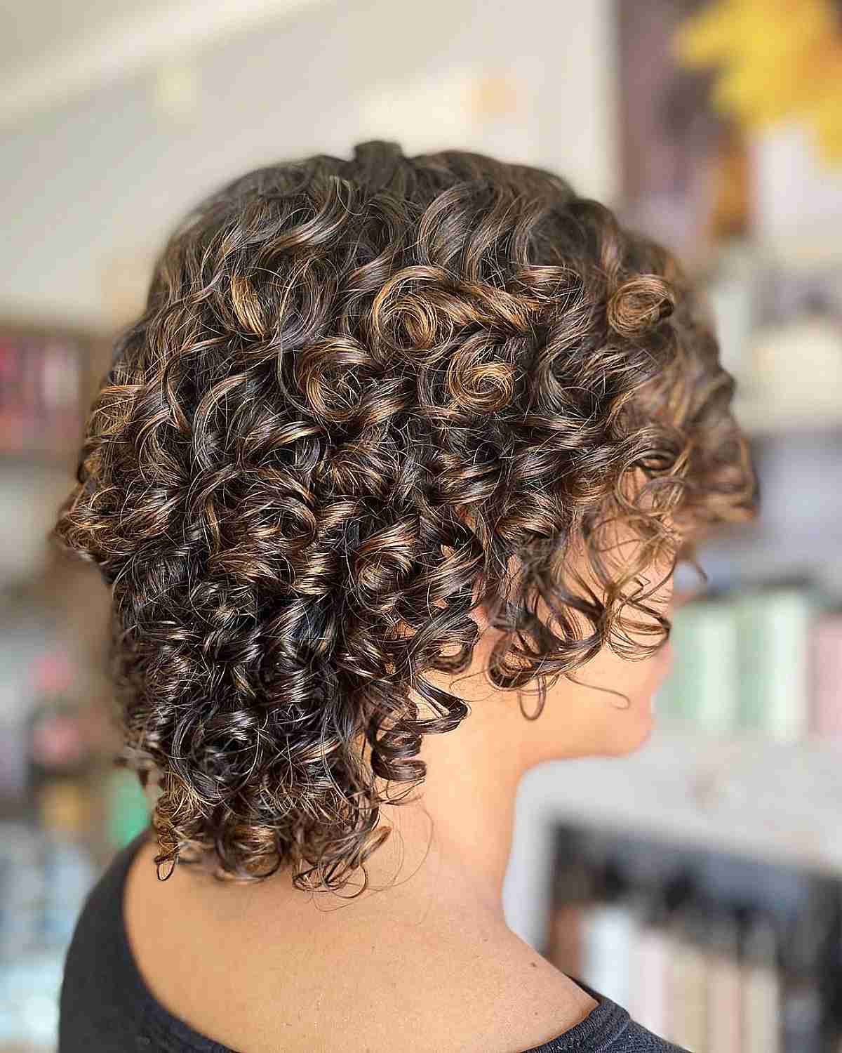 Short Layered Curly Hair with Subtle Pops of Honey Balayage