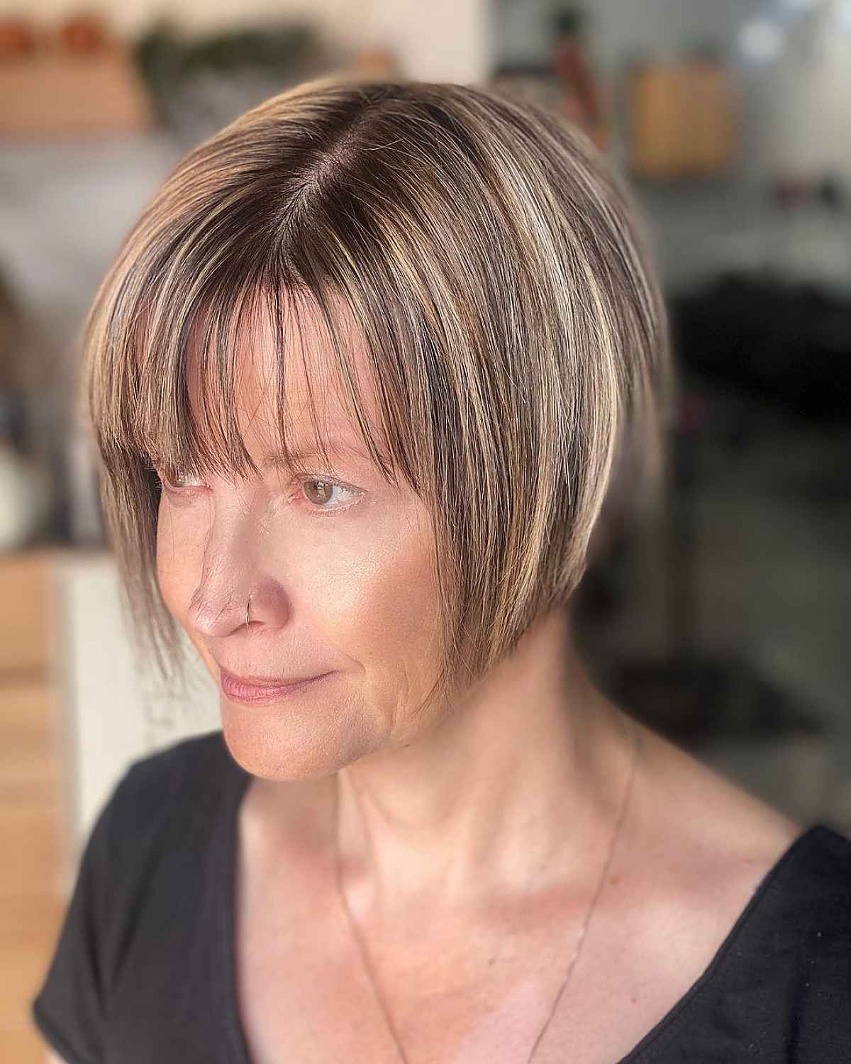 short layered haircut with wispy thin bangs and blonde highlights