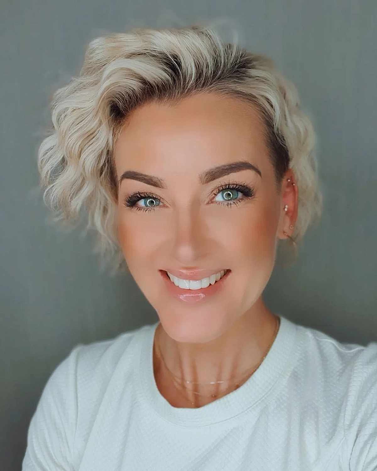 Short Light Blonde Frizzy Curls with Dark Roots