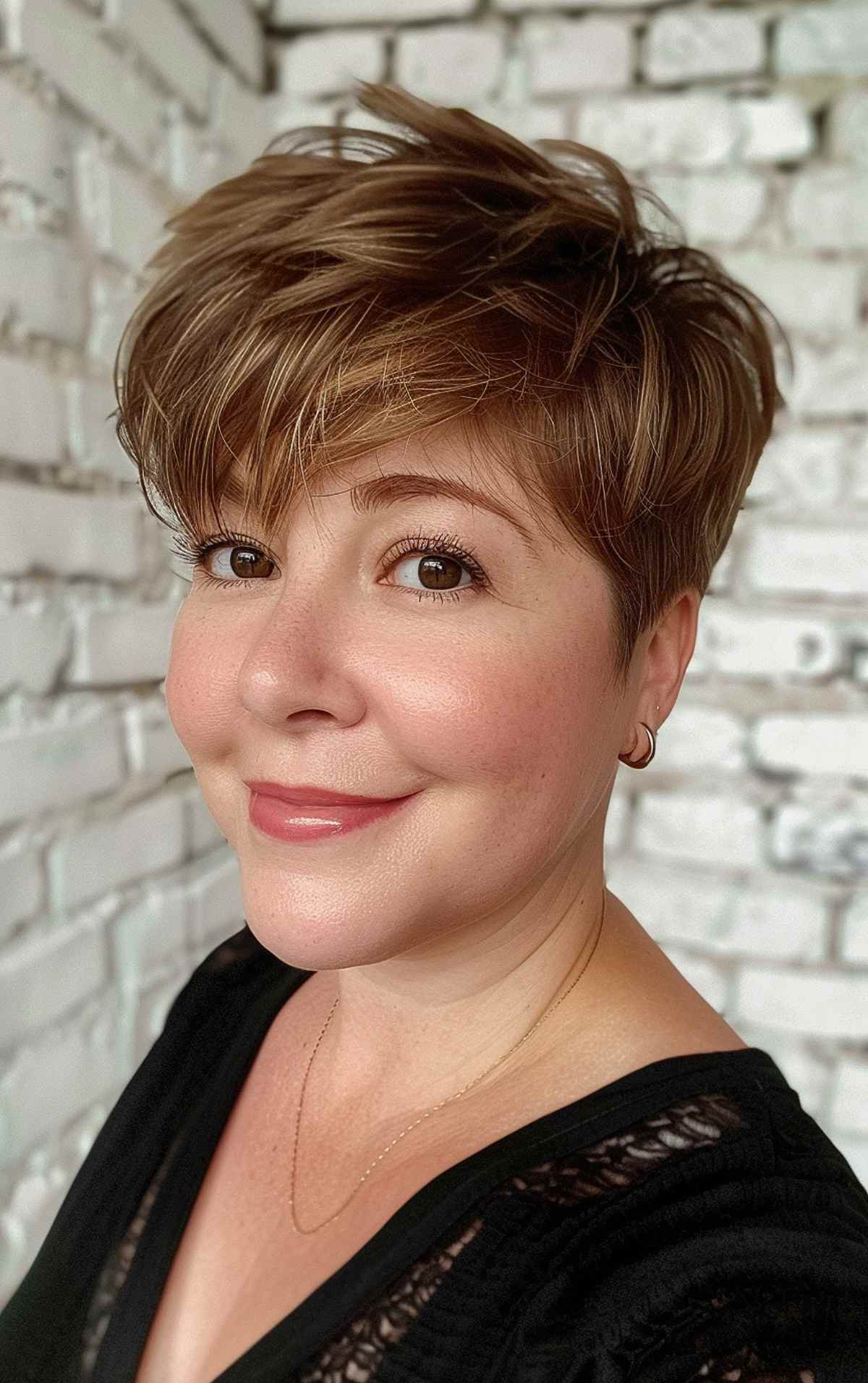 Short, tousled light brown pixie cut with soft highlights and wispy bangs