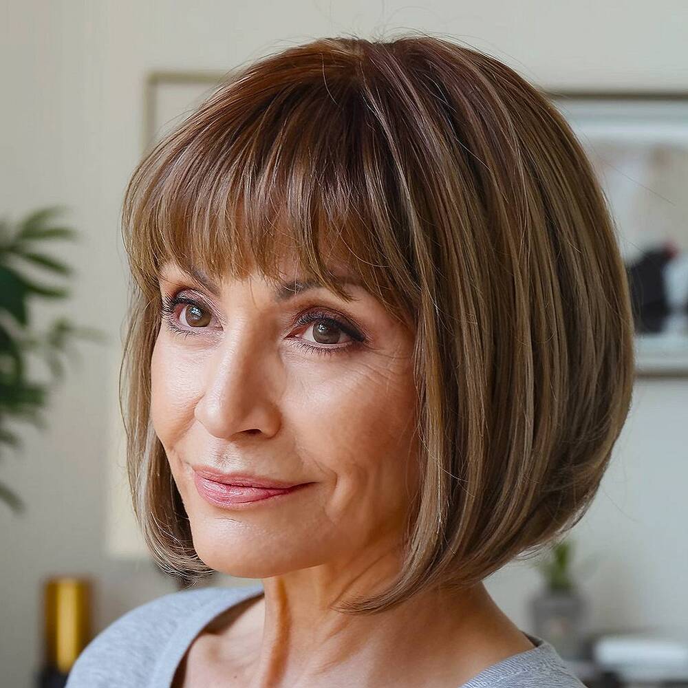 Short straight bob with fringe, a sleek and structured haircut that adds youthful charm for women over 60