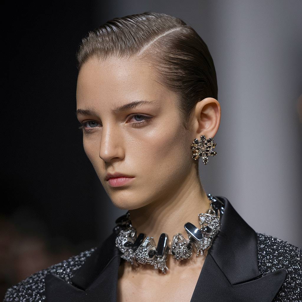 Sleek, ultra-short slicked-back hairstyle with a deep side part for a bold, high-fashion finish