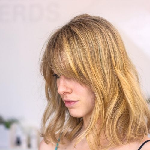 Modern shoulder-length honey blonde highlights with side bangs