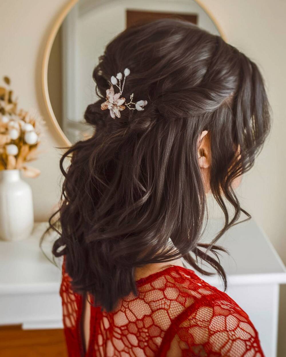 Elegant half-up, half-down prom hairstyle on shoulder-length hair with soft waves and a floral hairpin