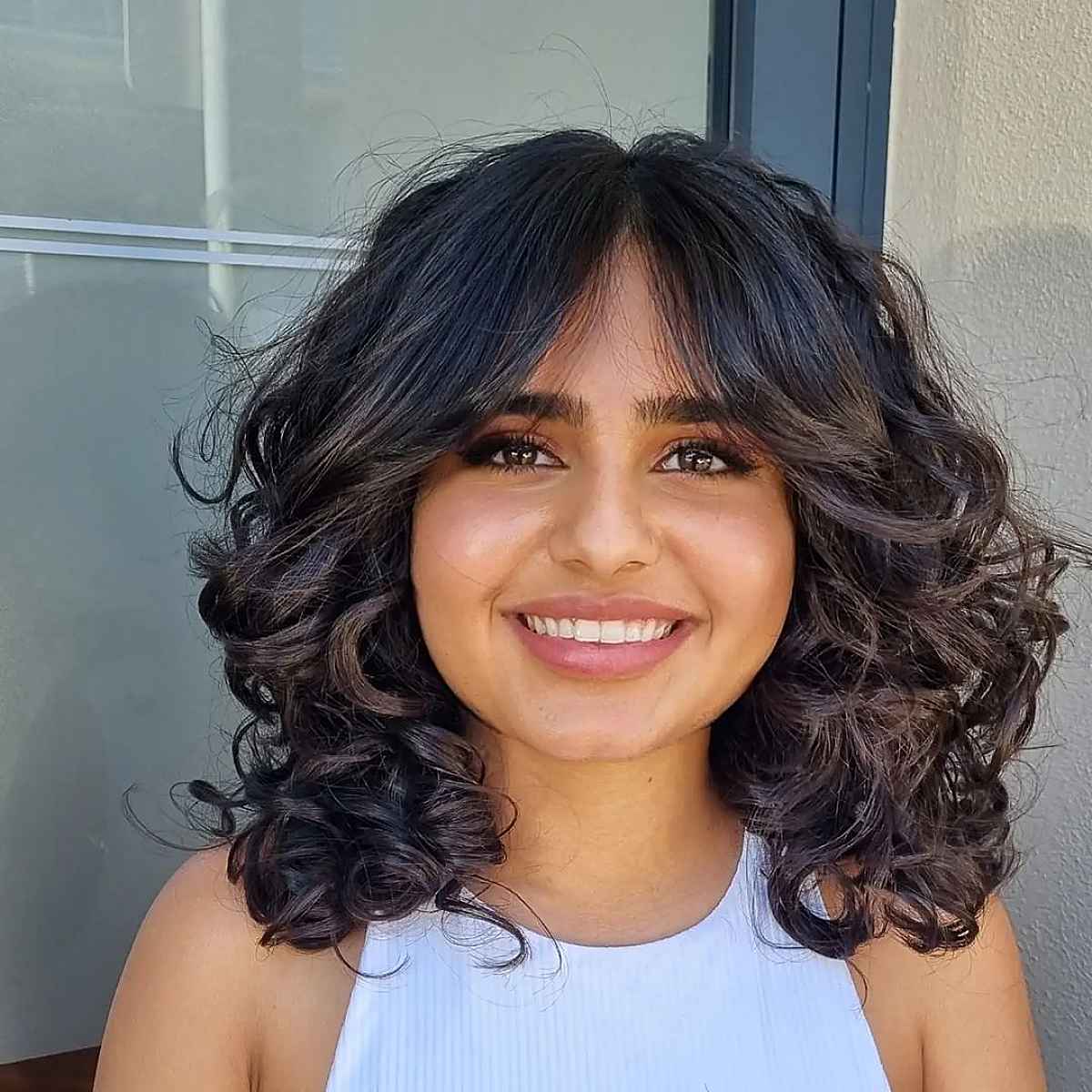 Shoulder-Length Wavy Curls with curtain bangs for a Round Face