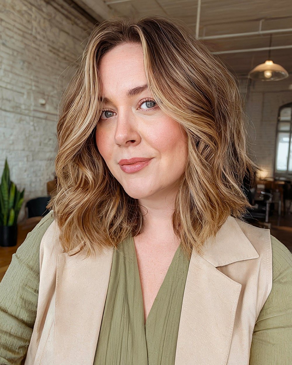 Shoulder-length wavy haircut with subtle blonde highlights for round-faced women over 40