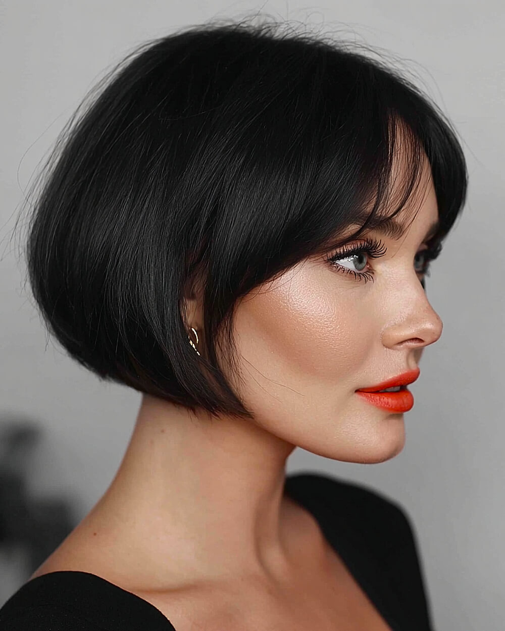 Sleek jaw-length bob with wispy bangs on thick straight hair, perfect for defined jawlines and oval face shapes