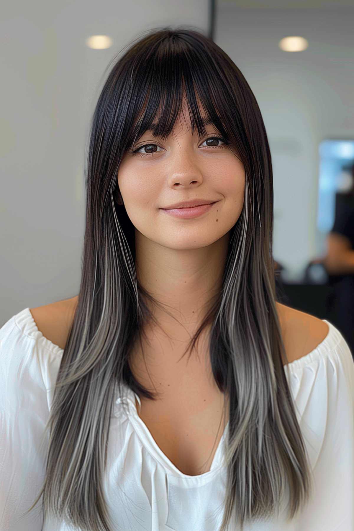 Woman with sleek long hair, blunt bangs, and ash blonde highlights