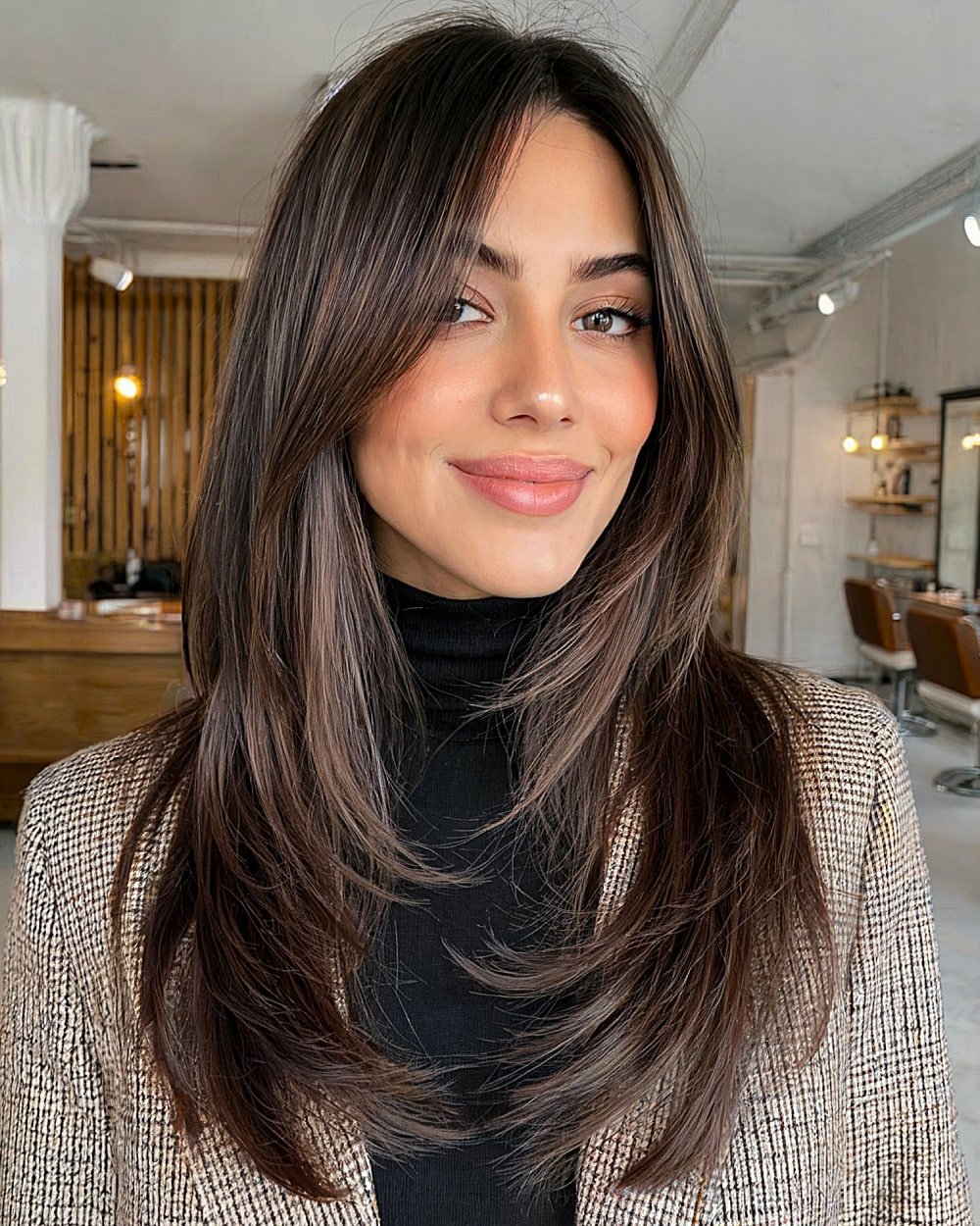 Long sleek layered haircut with feathered ends and soft curtain bangs