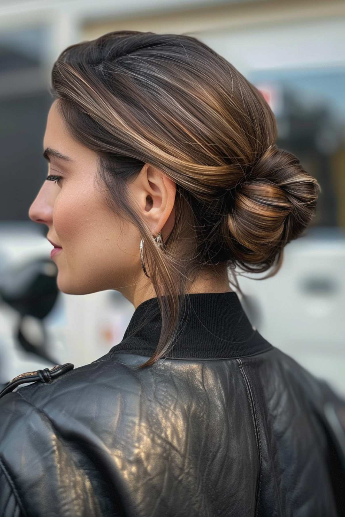 Woman with a sleek low bun in a biker jacket