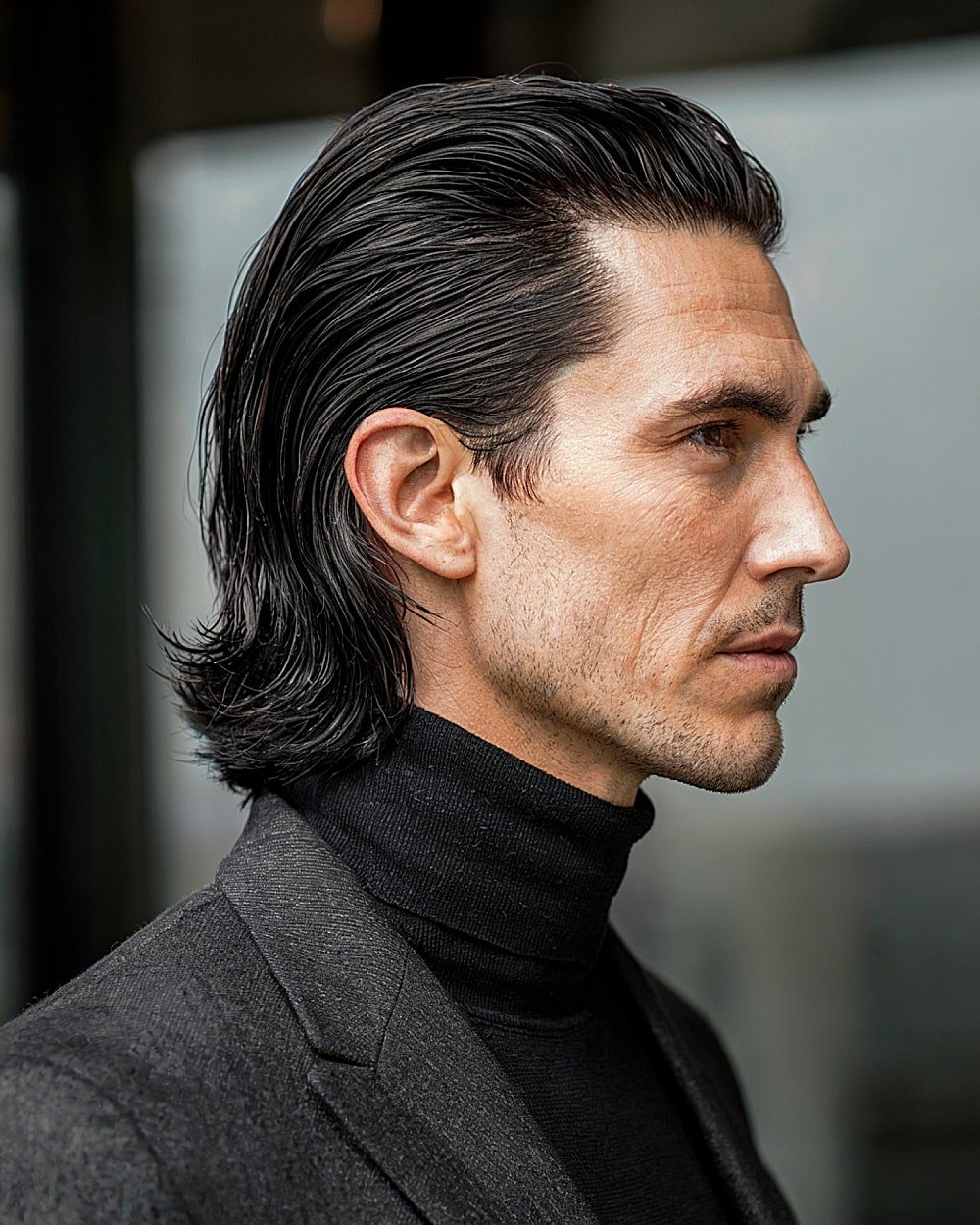Slicked back medium-long haircut with clean side profile for men