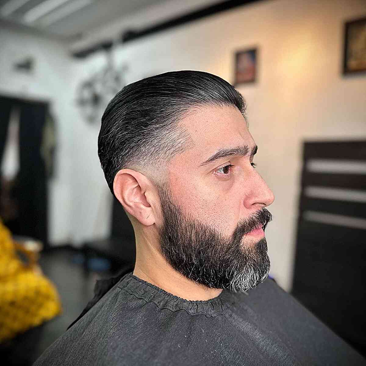 Slicked Back Straight Hair with Low Fade for Mature Men with Beard