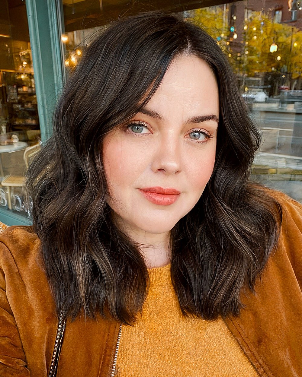Dark brunette blunt cut styled with soft waves for medium hair on women over 40 with round faces
