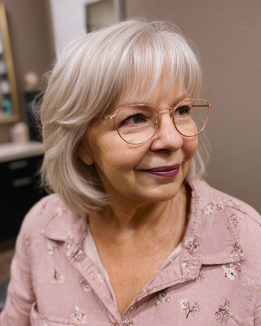 Soft feathered haircut with wispy bangs for women in their 70s, styled on straight silver hair for volume and softness
