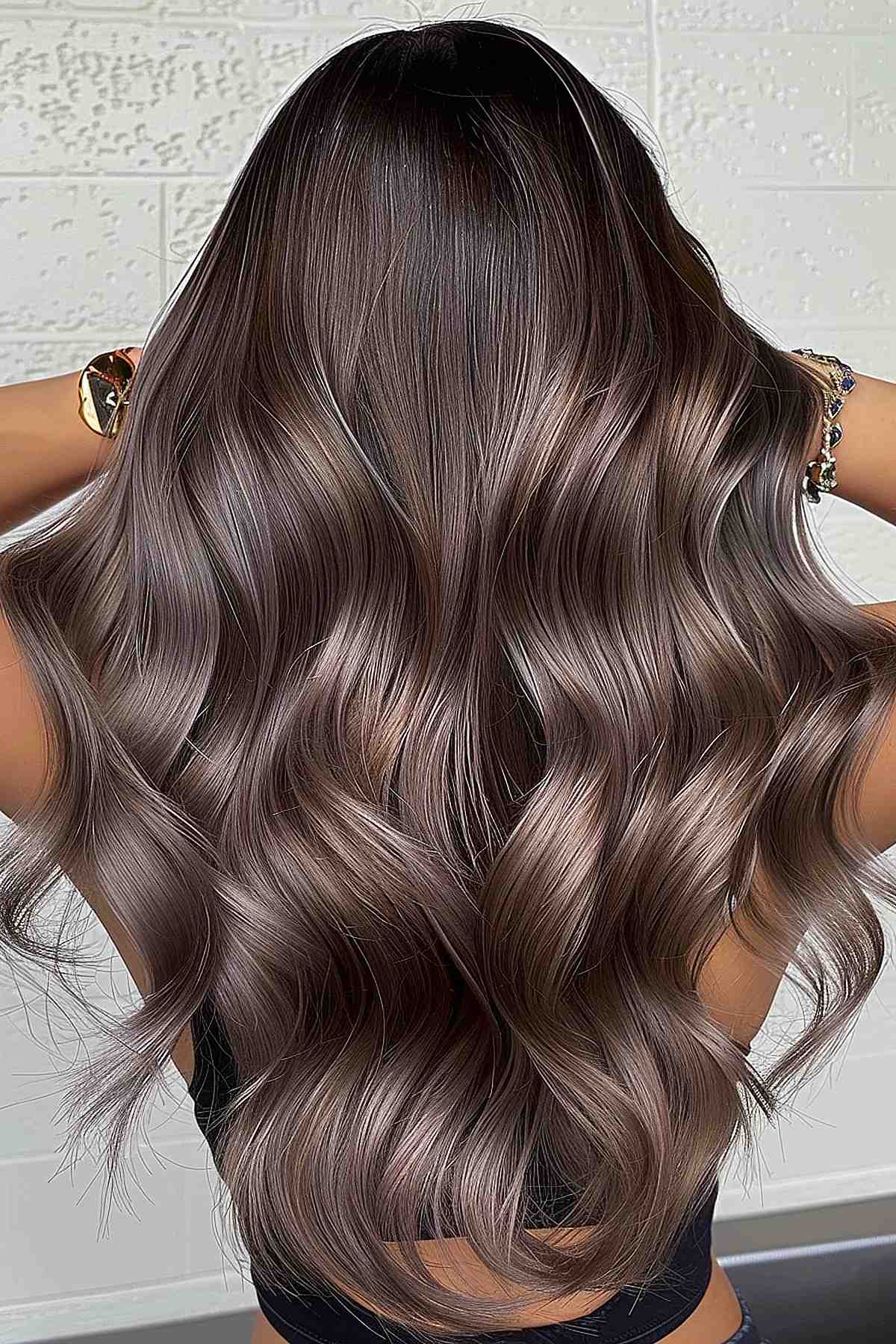 Long, thick waves in a gradient of mushroom brown tones, showing depth and subtle elegance in hair color.