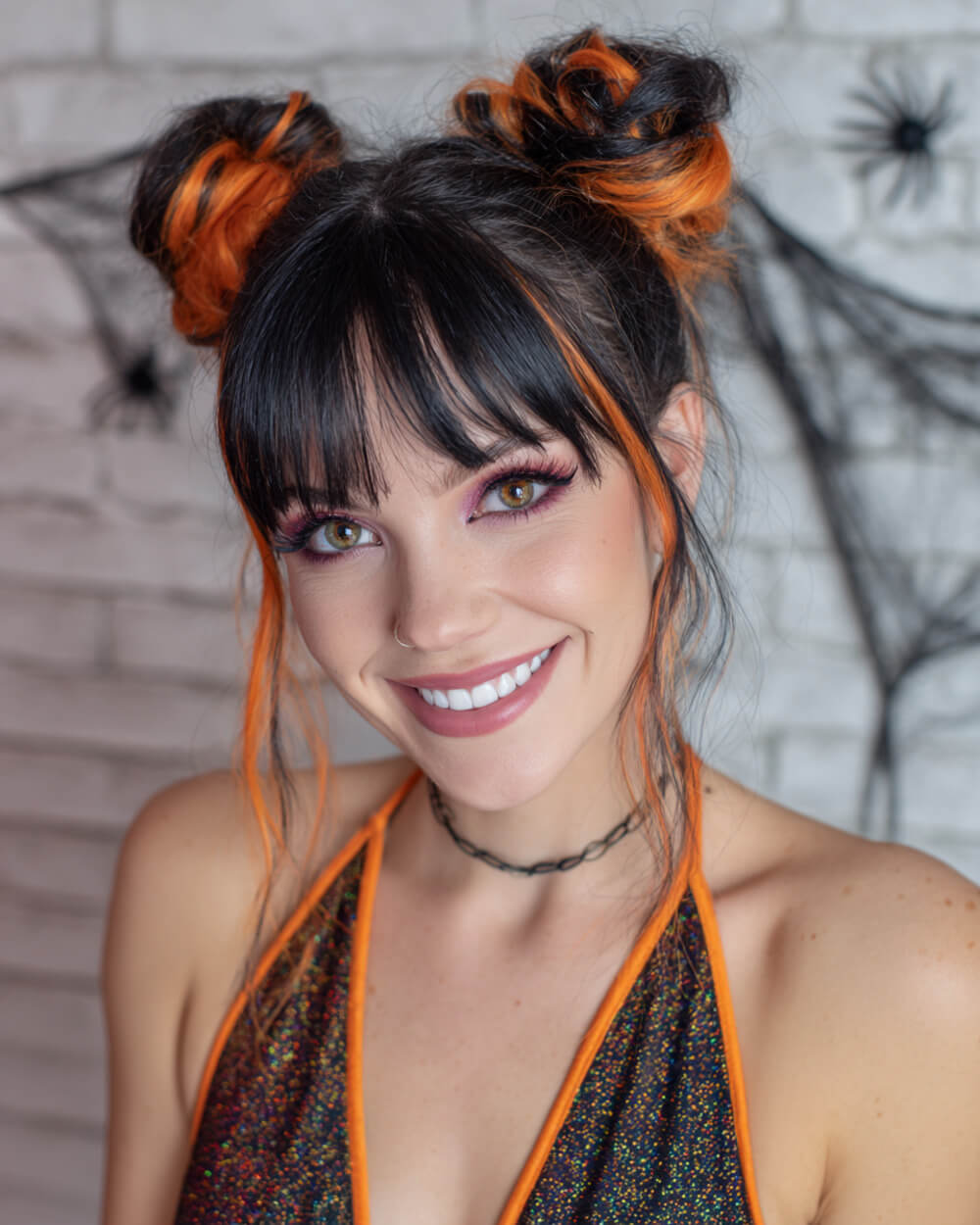 Space buns with black hair and orange streaks, playful Halloween hairstyle