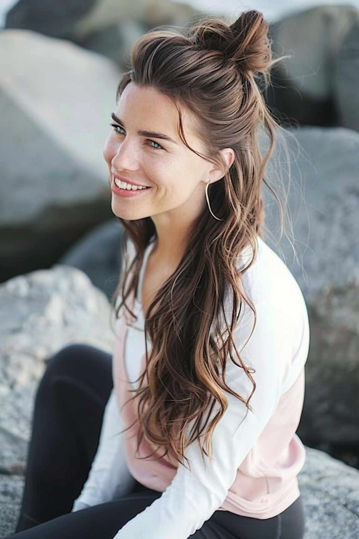 Woman with a sporty half-up half-down hairstyle featuring a loose high bun and flowing wavy hair, ideal for both active and social settings.