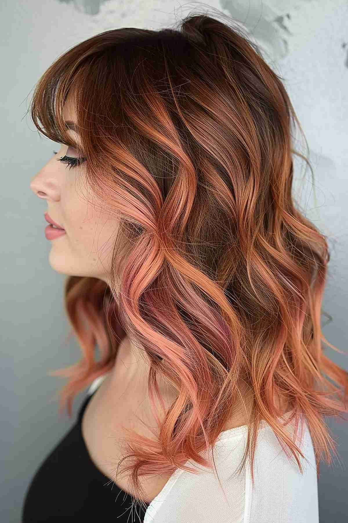 Soft wavy hair with subtle peach highlights over a rich brown base, adding depth and a playful twist, ideal for enhancing warmer skin tones.