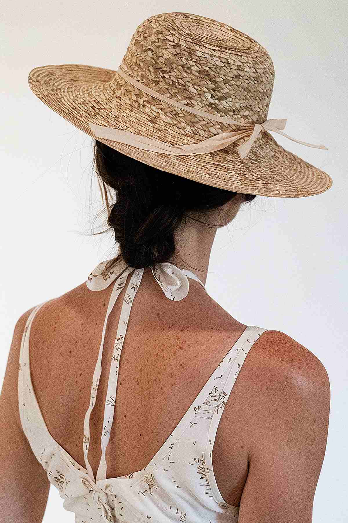 Rear view of a woman with a low bun hairstyle under a sun hat, suitable for medium-length hair at the waterpark