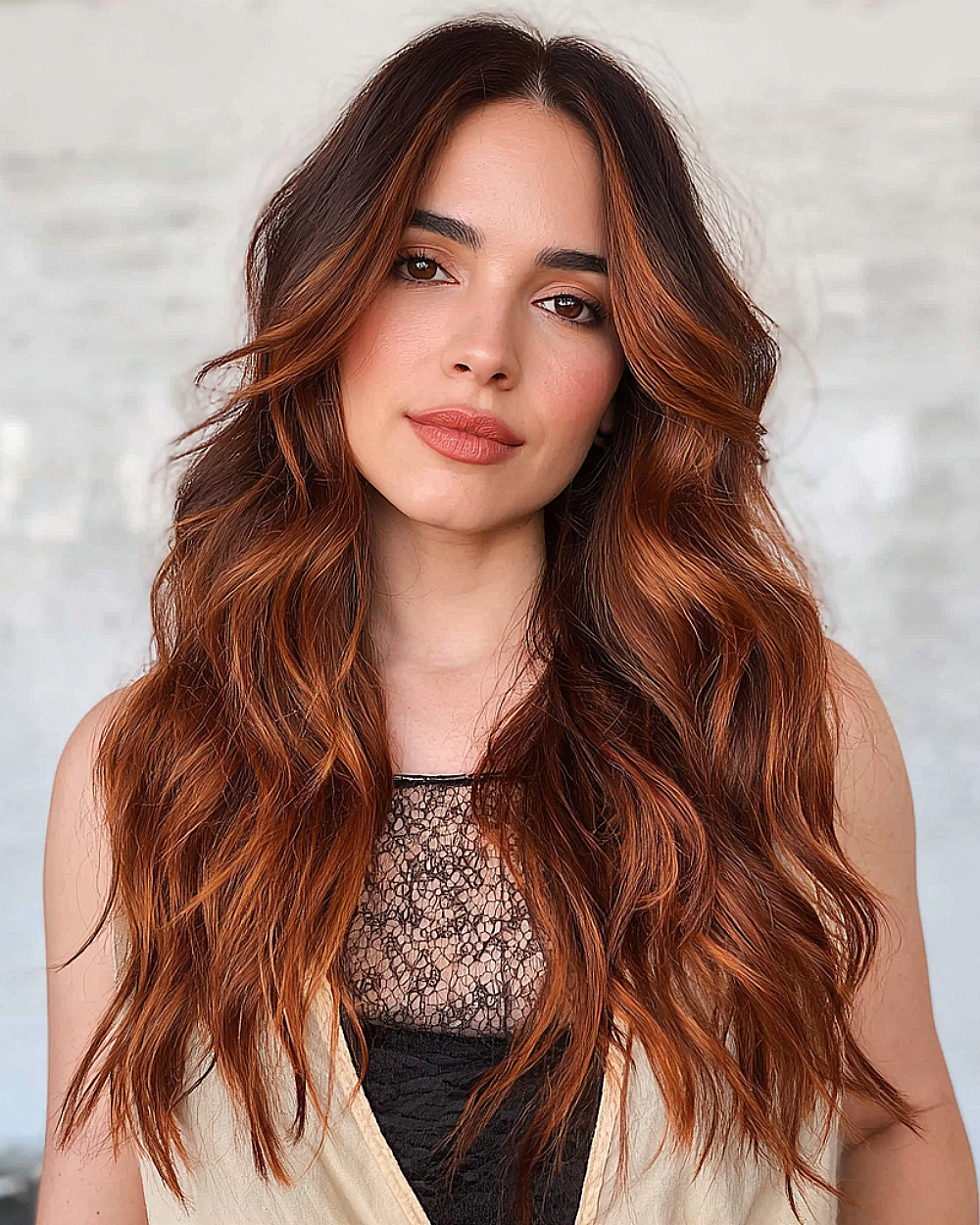 Sunset-toned copper balayage on long wavy hair with dark roots and face-framing highlights